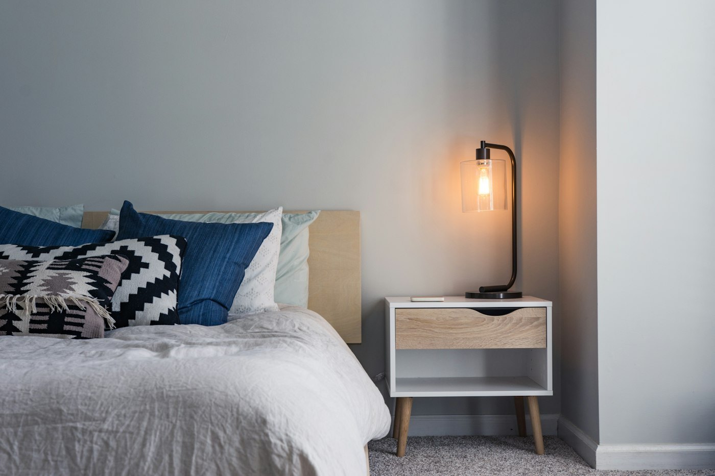 Standard Room — queen bed with navy feature wall, wool throw and warm bedside light